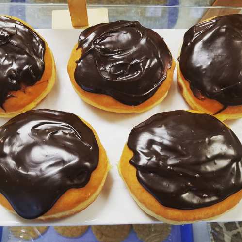 A platter of six round donuts topped with glossy chocolate icing.