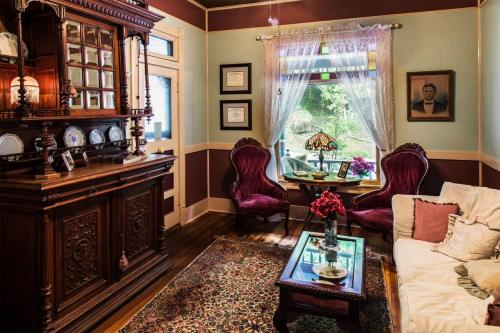Cozy vintage living room with ornate furniture, a window view, and decorative accents, featuring a floral arrangement.