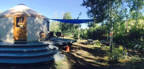 A cozy yurt on a wooden deck surrounded by trees and a peaceful outdoor setting.