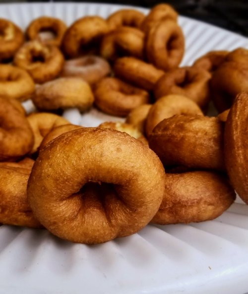 A close-up of golden-brown mini donuts arranged on a white plate.