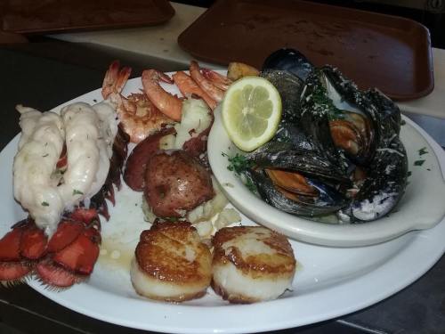 A seafood platter featuring shrimp, scallops, mussels, and potatoes, garnished with lemon slices.