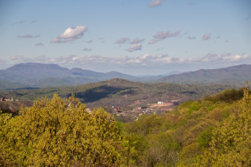 A scenic view of rolling mountains and lush green valleys under a partly cloudy sky.