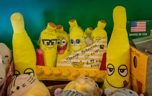 A collection of yellow plush banana toys, some with cartoon faces, displayed in a colorful box.
