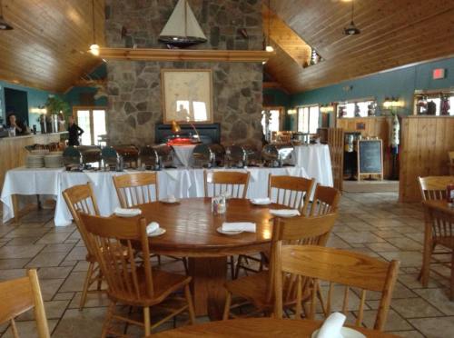A spacious restaurant interior with wooden tables, a stone fireplace, and a buffet setup against a rustic backdrop.