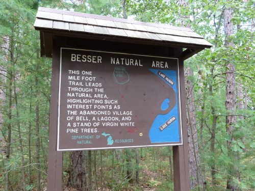 Sign for Besser Natural Area, detailing a one-mile foot trail and points of interest like an abandoned village and lagoon.
