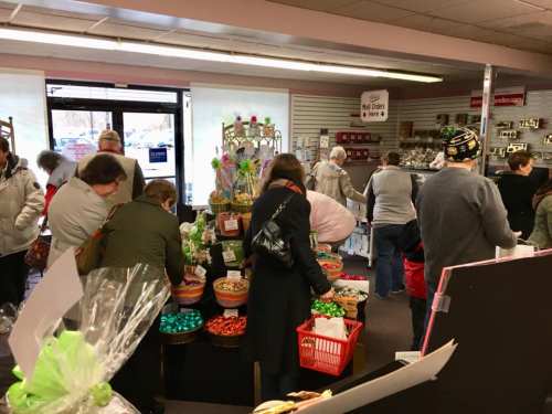 A busy store interior with customers browsing colorful displays of candy and gifts.
