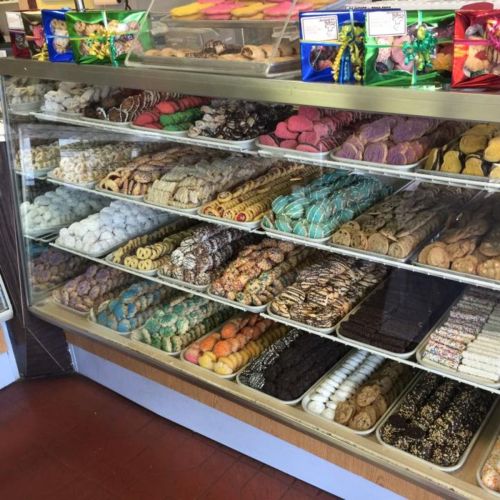 A display case filled with a variety of colorful cookies and pastries, neatly arranged on multiple shelves.