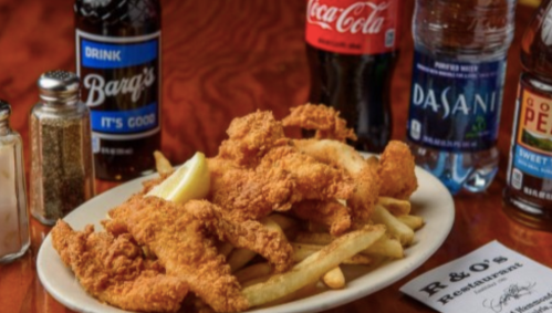 A plate of fried chicken and fries, accompanied by drinks and condiments on a wooden table.