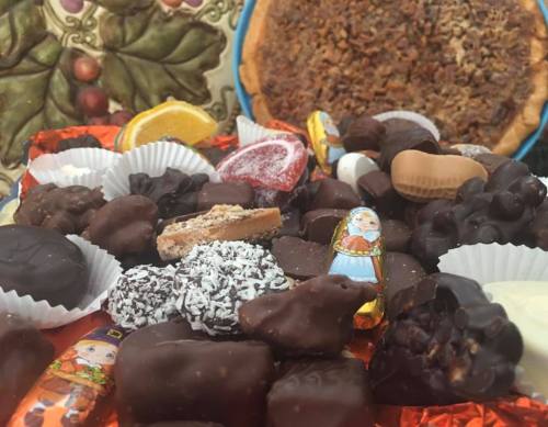 A colorful assortment of chocolates and candies, with a pecan pie in the background.