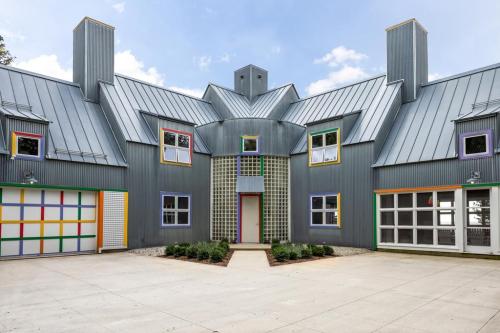 A modern, colorful building with a unique geometric design and multiple windows, surrounded by a paved courtyard.