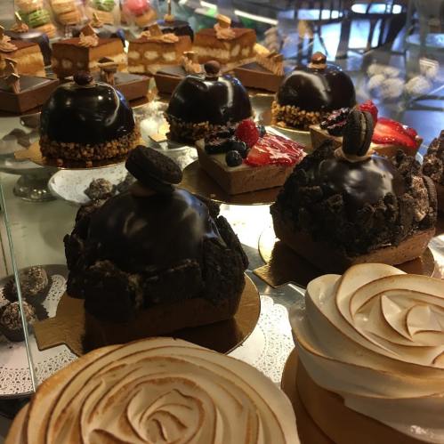 A display of various elegant desserts, including chocolate domes, fruit-topped pastries, and meringue swirls.