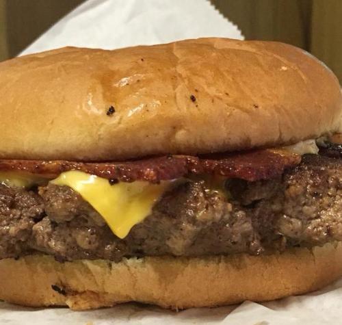 A close-up of a juicy hamburger with melted cheese and crispy bacon on a soft bun.