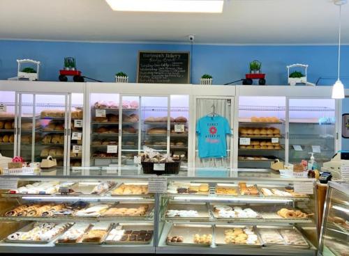 A bakery display case filled with various pastries and breads, with a menu board and decorative plants in the background.