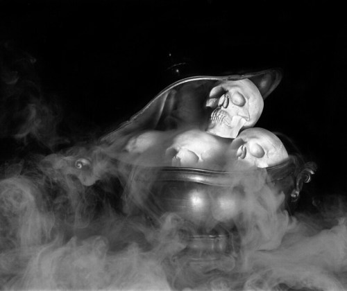 A silver bowl filled with skulls, surrounded by swirling mist, creating a spooky atmosphere.