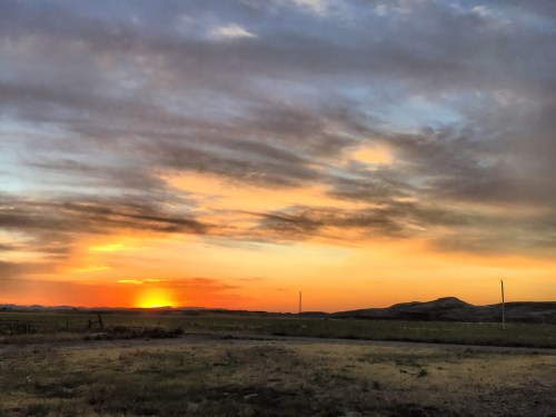 A vibrant sunset over rolling hills, with colorful clouds and a serene landscape in the foreground.