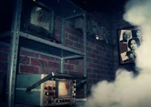 A dimly lit room with old monitors on a shelf, smoke swirling around, and a wall featuring black-and-white portraits.