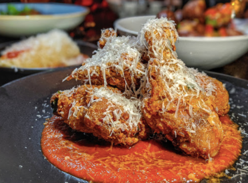 Crispy fried chicken wings topped with grated cheese, served on a bed of rich red sauce.