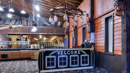 A rustic restaurant interior featuring a welcome sign, wooden decor, and hanging lanterns.