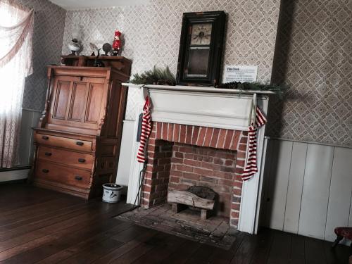 Cozy room featuring a brick fireplace with festive stockings, wooden furniture, and patterned wallpaper.