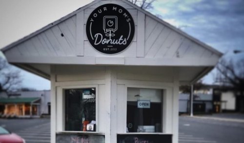 A small donut shop kiosk with a sign reading "Your Mom's Donuts" and an "Open" sign in the window.