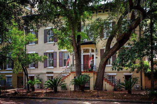 Historic building with a grand entrance, surrounded by lush greenery and palm trees, in a charming urban setting.