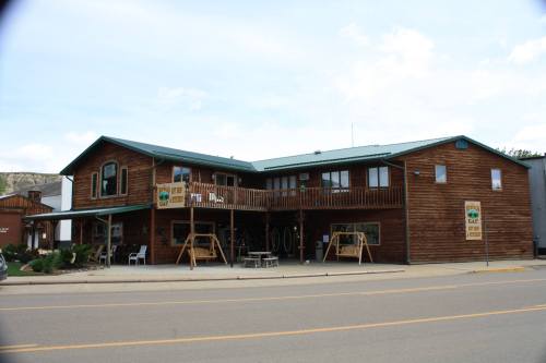 A two-story wooden building with a green roof, featuring balconies and signs, located on a street.