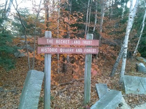 Wooden signs in a forest, reading "The Becket Land Trust" and "Historic Quarry and Forest," surrounded by autumn foliage.