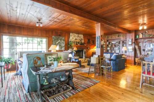 Cozy wooden living room with a fireplace, comfortable seating, and rustic decor, featuring a warm, inviting atmosphere.