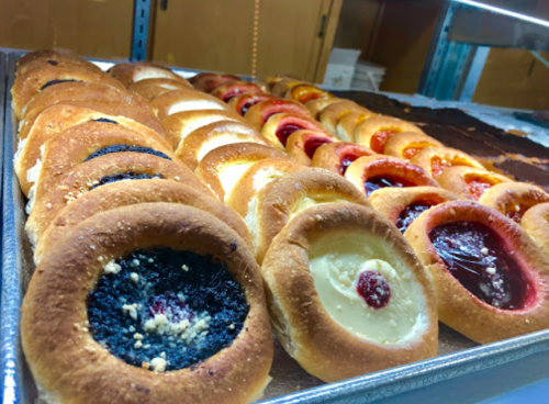 A tray of assorted pastries with various fillings, including fruit and cream, arranged in neat rows.