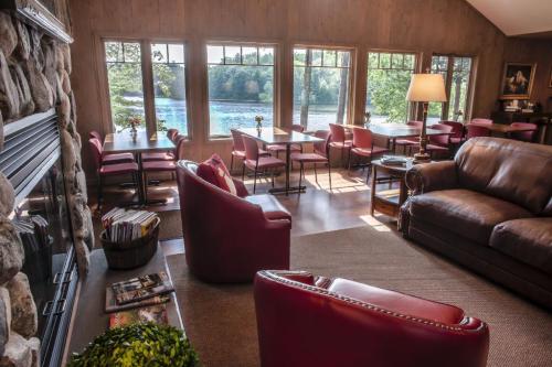 Cozy lounge with red chairs, a fireplace, and large windows overlooking a serene lake and trees.