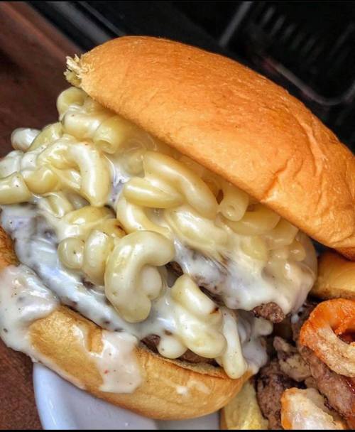 A close-up of a sandwich filled with macaroni and cheese, served on a soft bun.
