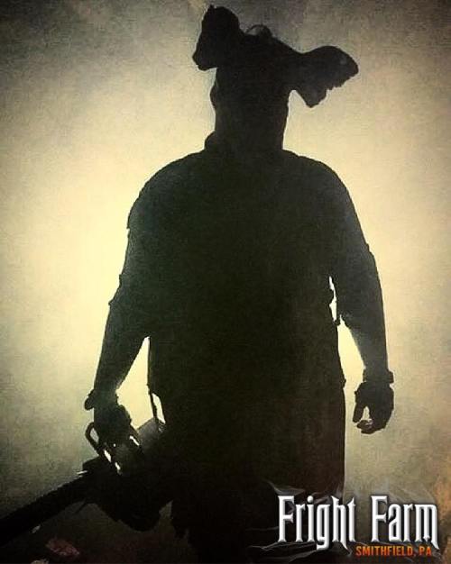 Silhouette of a figure holding a chainsaw, wearing a mask, set against a foggy background. Fright Farm logo in corner.