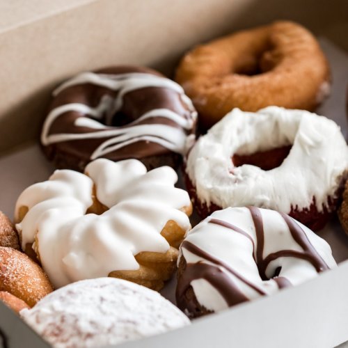 A box of assorted donuts, featuring chocolate, white icing, and a red velvet donut among others.