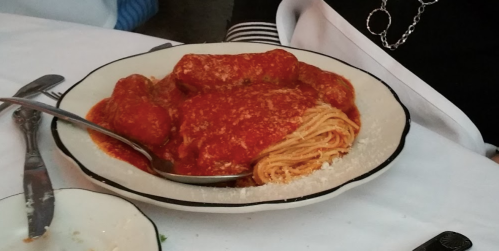 A plate of spaghetti topped with meatballs and marinara sauce, garnished with grated cheese.