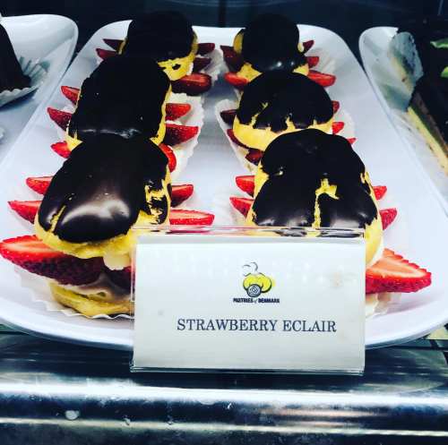 A display of strawberry éclairs topped with chocolate and garnished with fresh strawberries.
