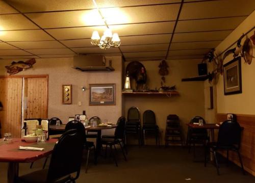 Cozy restaurant interior with wooden decor, tables set for dining, and mounted fish and animal trophies on the walls.