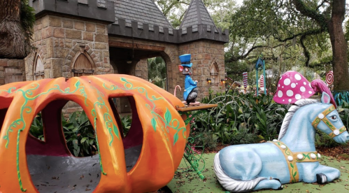 A whimsical scene featuring a colorful pumpkin carriage, a blue horse, and a castle backdrop in a vibrant garden setting.