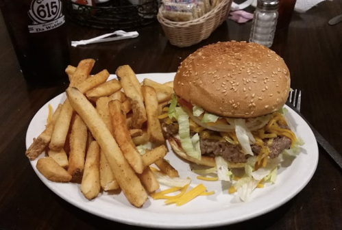 A plate with a sesame seed burger topped with lettuce and cheese, served with a side of golden French fries.