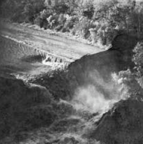 A black and white image of a waterfall cascading over rocky terrain, surrounded by trees and vegetation.