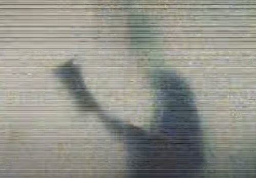 A blurred silhouette of a person with an arm raised, creating a shadow on a textured surface.