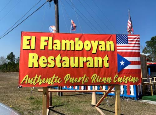Sign for El Flamboyan Restaurant featuring "Authentic Puerto Rican Cuisine" with a Puerto Rican flag and American flags.