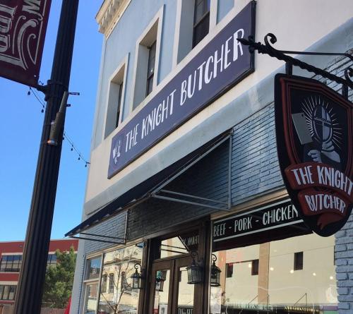 Exterior of "The Knight Butcher" shop, featuring a sign and storefront with blue walls and a clear sky.
