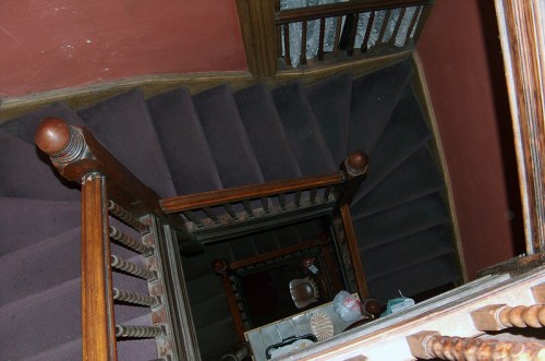 Aerial view of a wooden staircase with a carpeted surface, leading down to a lower level.