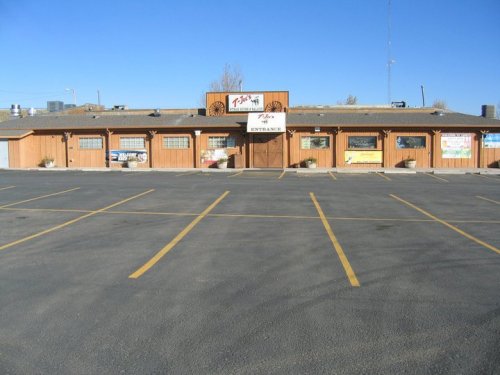 A wooden building with a sign reading "Entrance" and several banners, set in a large empty parking lot.