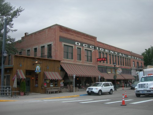 Historic Occidental Hotel with a brick facade, awnings, and a wooden storefront, set against a cloudy sky.