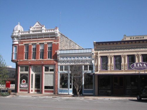 Historic buildings with ornate facades line a street under a clear blue sky.