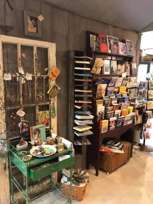 A cozy shop interior featuring a vintage door, jewelry display, and shelves filled with books and trinkets.