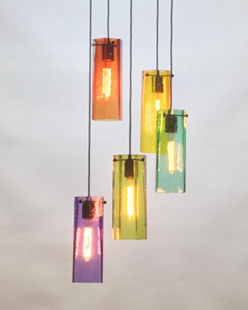 Five colorful pendant lights hanging against a cloudy sky, emitting a warm glow.