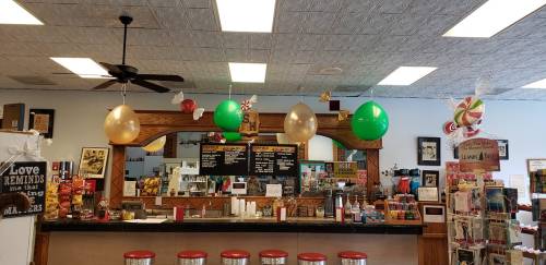 A colorful diner interior with balloons, a menu board, and a counter with red stools.