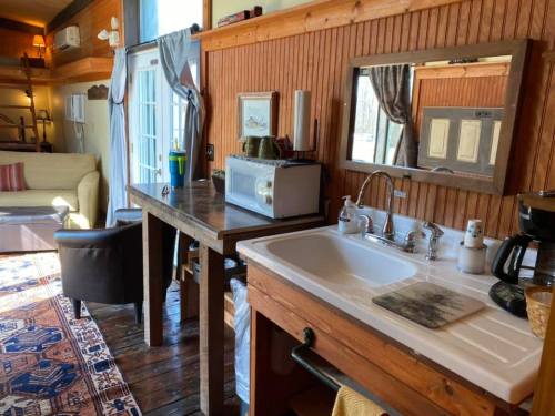 Cozy kitchen area with wooden accents, a sink, microwave, coffee maker, and a view of a living space.